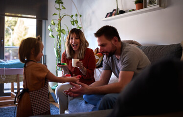 Cheerful family at home, playing with his daughter in the living room.