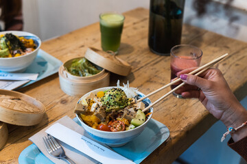 Woman eating asian food with chopstick at restaurant