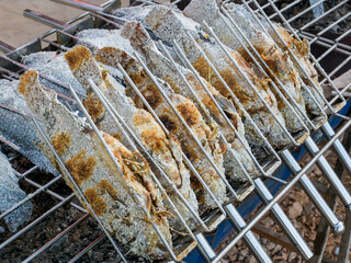 Grilled salted tilapia fish on charcoal grill at the market