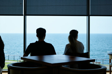 A silhouette of a man and woman sitting side by side with a view of the sea.
