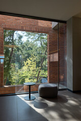 A cafe with a view of a dense forest through a large glass window. Simple and modern table and chairs.