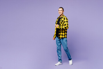 Full body side profile view young middle eastern man he wear yellow shirt casual clothes walking going look camera isolated on plain pastel light purple background studio portrait. Lifestyle concept.