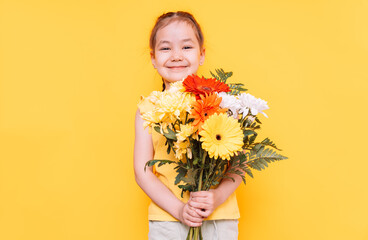 Little girl with a large bouquet of colorful flowers in front of a yellow background