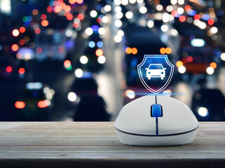 Car with shield flat icon on wireless computer mouse on wooden table over blur colorful night light...