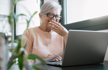 Cheerful old caucasian businesswoman laughing working online watching funny webinar podcast on...
