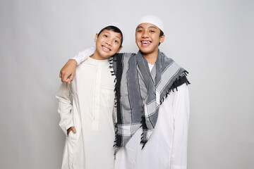 Two Muslim boys in white robe smiling happily isolated on white background