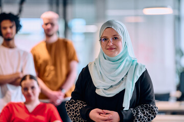 A diverse group of young business people walking a corridor in the glass-enclosed office of a...