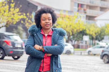 Fototapeta premium afro woman with crossed arms and winter jacket on the street