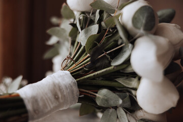 A bouquet of white flowers with green leaves and a white ribbon. The flowers are arranged in a way...