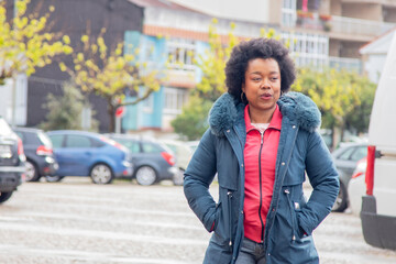 afro woman in winter jacket walking in the city