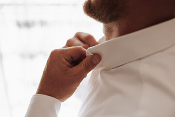 A man is getting dressed and adjusting his collar. Concept of routine and orderliness, as the man...