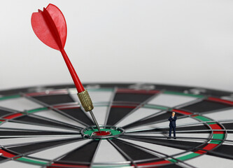 Fototapeta premium The red dart arrow in the middle of the dart paper is the goal of the business. An entrepreneur looking at arrows on a dartboard. Concept of business marketing plans and objectives. 