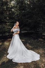 Fototapeta premium A woman in a white dress is standing in a forest