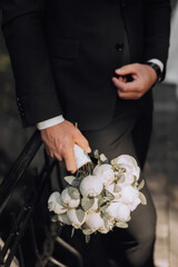 A man in a suit holding a bouquet of white flowers. Concept of elegance and sophistication, as the man is dressed in a suit and tie, and the flowers are a symbol of love and romance