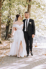Naklejka premium A bride and groom are walking down a path, with the bride holding a bouquet. Scene is happy and romantic, as the couple is celebrating their wedding day