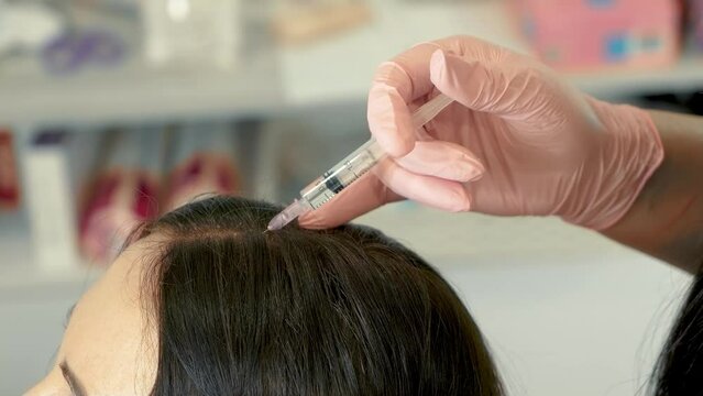Injection with syringe and needle. Beautician doctor makes injections into head for hair growth. Mesotherapy for hair growth and strengthening in beauty salon. Vertical orientation. Anti aging