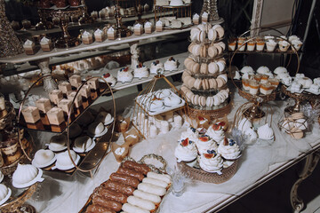 A table full of desserts including cupcakes, macaroons, and other sweets. The desserts are arranged...