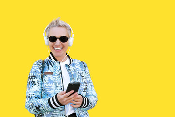 Middle Aged Woman, Short HairStyle, Casual Look With White Headphones On Yellow Background. Active...