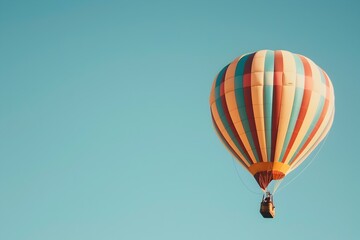 Obraz premium Whimsical Striped Hot Air Balloon Floating Peacefully Across a Clear Blue Sky on a Serene Aerial Adventure
