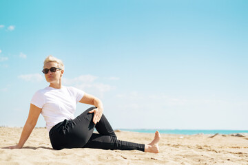 Middle Aged Female Doing Spinal Twist Yoga Exercises. Mindfulness Zen Spiritual Meditation Tips. Kundalini Yoga. Reiki Meditation. Relaxing. Unity With Nature. Sea or Ocean Coast Beach