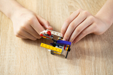 boy created and manipulates with transformer robot, child plays with colored plastic parts...