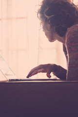 Side view of laying woman using laptop at home on the couch. One modern female people surfing the...