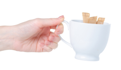 Sugar sticks in hand and white cup on white background isolation