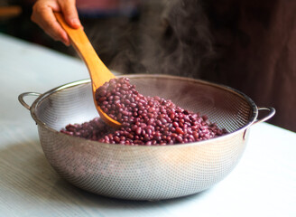 Boiled azuki beans, woman's hand release temperature by using wooden ladle scoop boiled azuki beans...