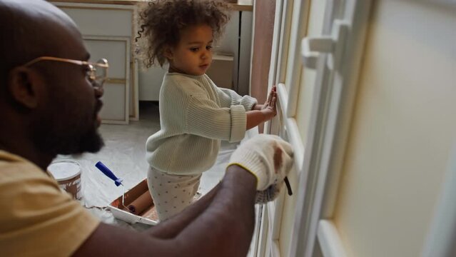 Side footage of baby helper holding one edge of measuring tape for dad to take measure on door during home improvements