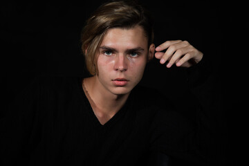 Fototapeta premium A young attractive guy is resting. Black background.