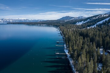 Pier, mountains with snow on calm Lake Tahoe, Homewood, California, United States of America.