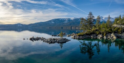 Boulders, sandy beach, forest and snowy mountains on a calm Lake Tahoe. Incline Village-Crystal...