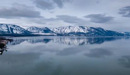 Calm mirror Lake Tahoe and mountains with snow. Tahoe Keys, South Lake Tahoe, California, United States of America.
