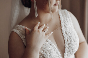A woman wearing a wedding dress and a ring on her left hand. The dress is white and has a lace...