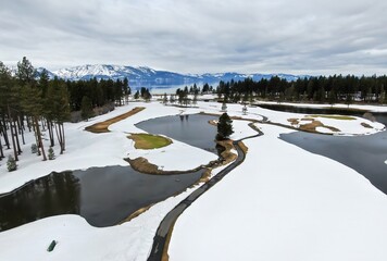 Golf course covered in snow, moutains and forest and calm Lake Tahoe. Stateline, Nevada, United...