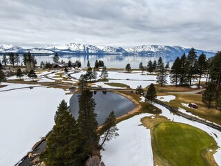 Golf course covered in snow, moutains and forest and calm Lake Tahoe. Stateline, Nevada, United...