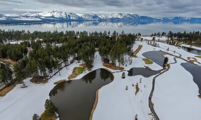 Golf course covered in snow, moutains and forest and calm Lake Tahoe. Stateline, Nevada, United States of America.