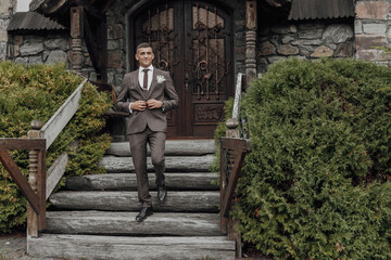 A man in a suit is walking up a set of stairs. The image has a formal and elegant mood, with the man dressed in a suit and tie. The setting appears to be a building with a stone exterior