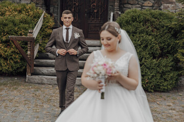 A bride and groom are standing in front of a church door. The bride is holding a bouquet of flowers