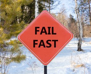 Fail fast symbol. Concept words Fail fast on beautiful red road sign. Beautiful forest snow blue sky background. Business and fail fast concept. Copy space.