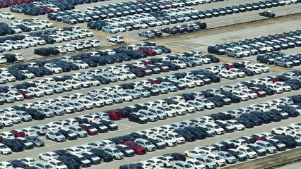 A breathtaking aerial reveals rows of pristine new cars, glistening in the sun, at a distribution...