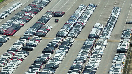 From the sky, a mesmerizing sight unfolds - a sea of pristine new cars resting in perfect...