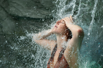 beautiful young cute sexy redhead woman in bikini, enjoy the splashing rippling water of the waterfall feels the falling water, in the Spa Wellness pool