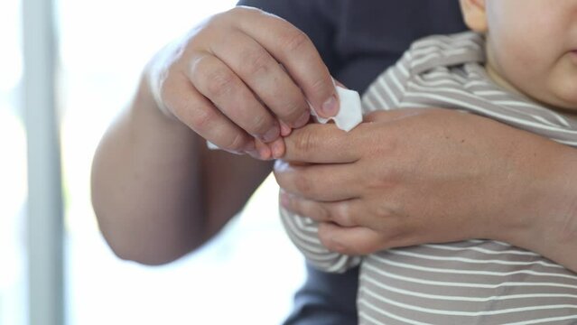 Mummy cleaning baby hands by an antibacterial wipe, healthcare concept