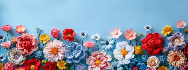 Multicolored knitted flowers banner on the blue background with copy space.