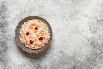 Sauerkraut with cranberries and carrots in a bowl on grunge background. Top view, flat lay, copy space.