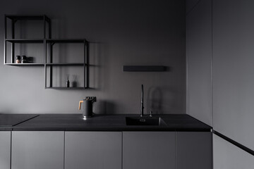 Black kitchen with electric kettle and sink for washing dishes built into the countertop