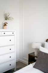 Bedroom with white chest of drawers near comfort bed with lamp on side table