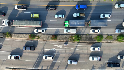 An intercity motorway, gridlocked with cars, stands still amidst a chaotic traffic jam. A drone captures the frustration from above. Traffic and vehicle concept. Road and cars background. Thailand.
