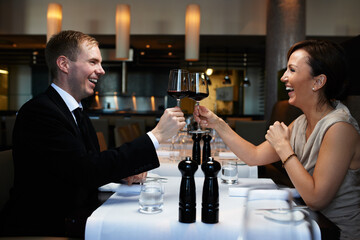 Couple, dinner and wine glass for cheers at table, celebration and anniversary in restaurant. Happy, alcohol and smile for toast with man and wife, marriage and romantic for luxury date at night - obrazy, fototapety, plakaty